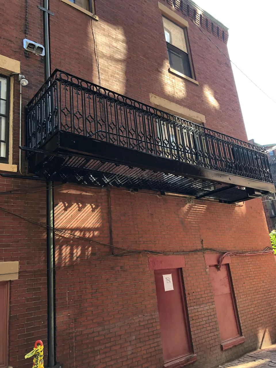 Black ornamental metal balcony railing and platform on a red brick building