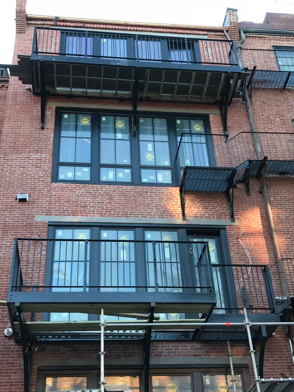 Black steel balconies with railings across the rear of a multi-story brick building