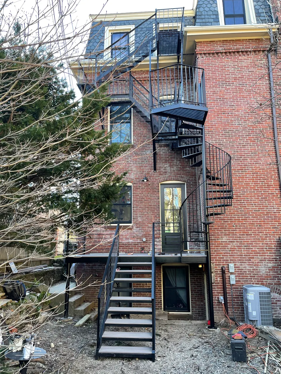 Black steel stair and spiral stair at the rear of a brick townhouse