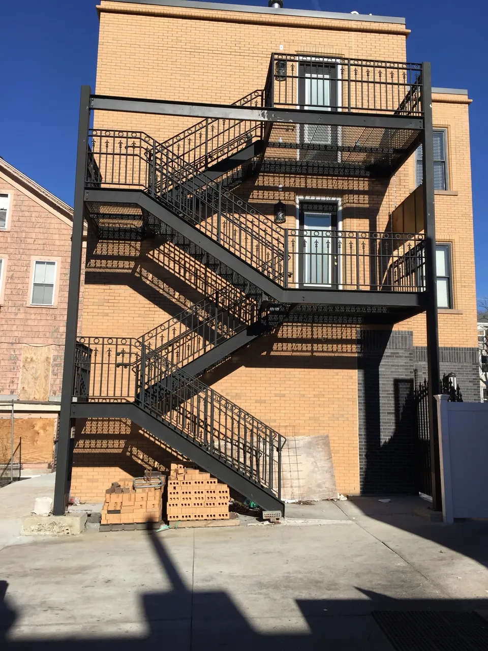 Multi-level black steel exit stairs and landings on the back of an orange brick building