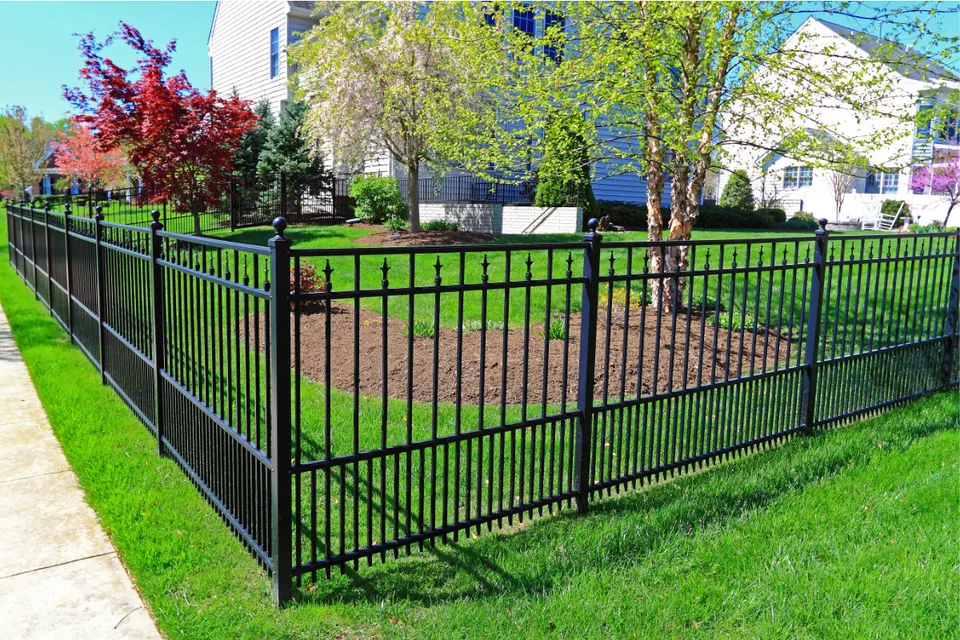 Black steel picket fence enclosing a landscaped lawn