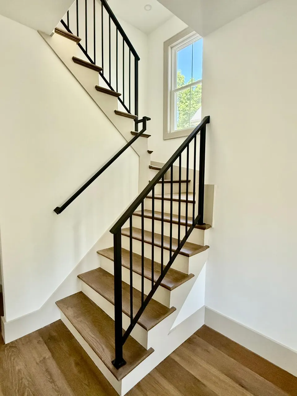 Black railing and wall handrail on a wood-tread stair turning at a landing