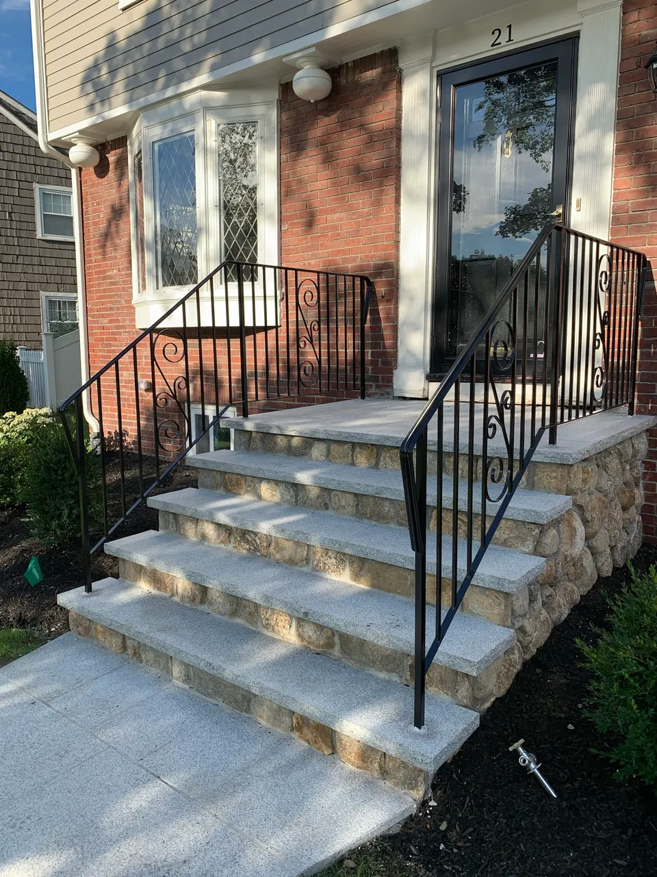 Black picket handrails with scroll accents beside granite entry steps