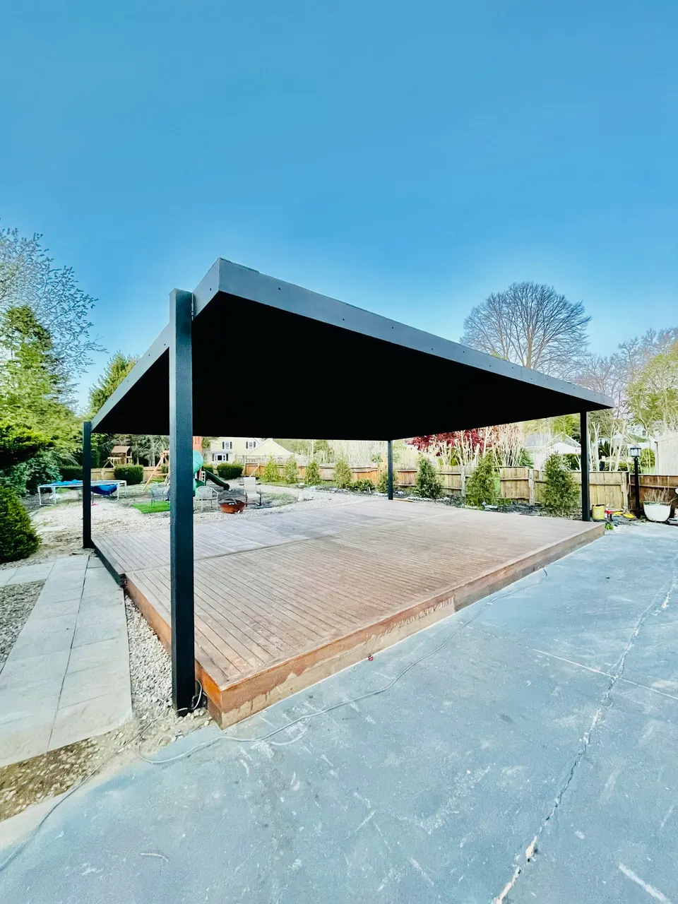 Black steel canopy over a wood deck in a backyard